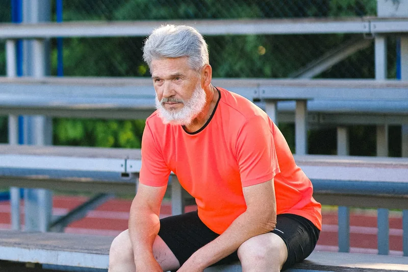 Older runner pausing on a track during a recovery interval