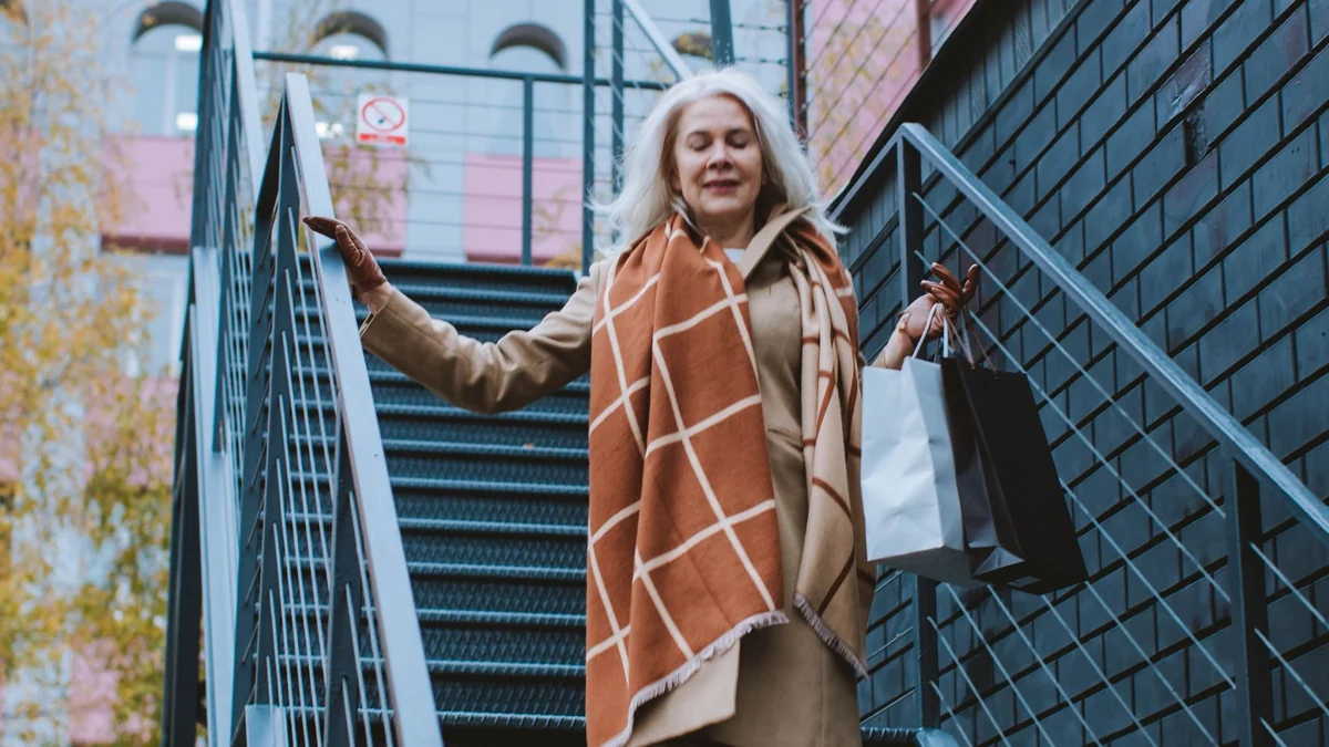 Mature woman carrying shopping bags while walking down outdoor stairs