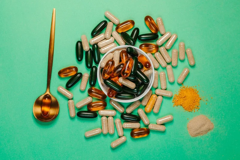 Capsules and powdered supplements arranged on a green background